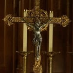 Crucifix with the corpus of Christ flanked by candles in the sanctuary